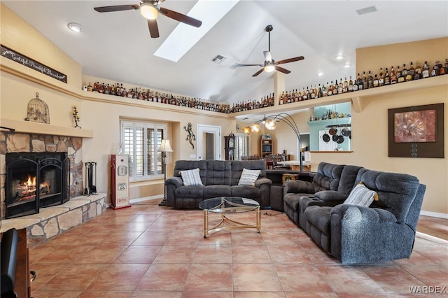 living area featuring light tile patterned floors, visible vents, a ceiling fan, vaulted ceiling, and a fireplace