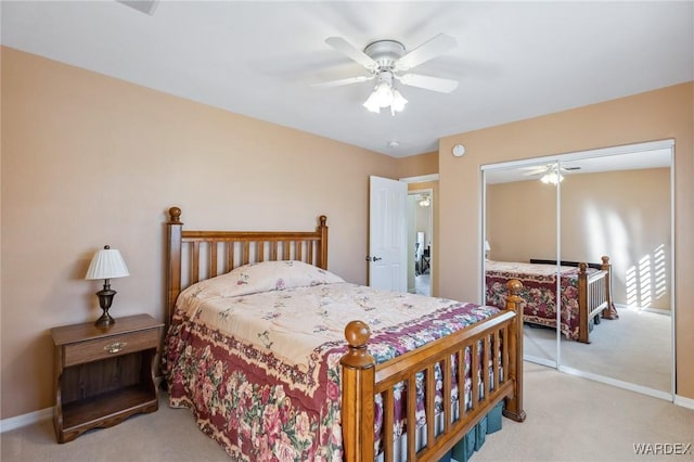 bedroom with a ceiling fan, a closet, light carpet, and baseboards