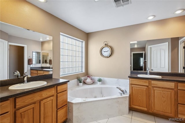 bathroom with a whirlpool tub, tile patterned flooring, visible vents, and a sink