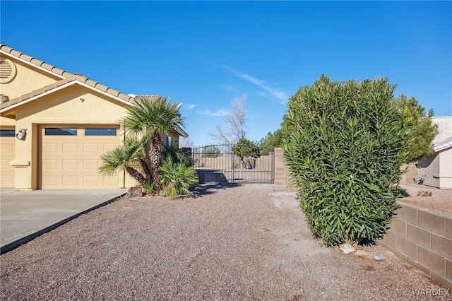 view of yard with a garage, driveway, a gate, and fence