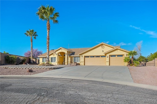 mediterranean / spanish house featuring driveway, an attached garage, fence, and stucco siding