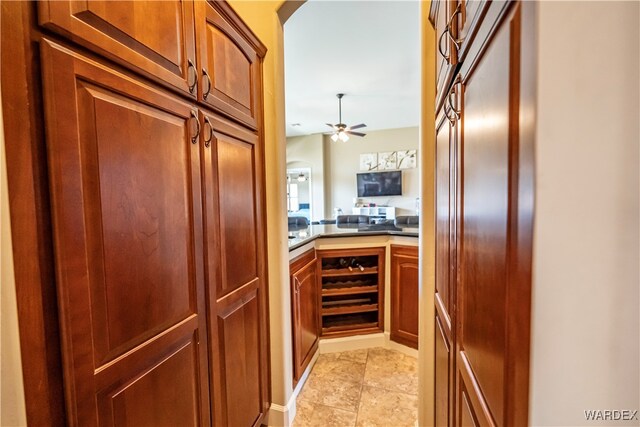 kitchen featuring ceiling fan, brown cabinets, open floor plan, light countertops, and light tile patterned flooring