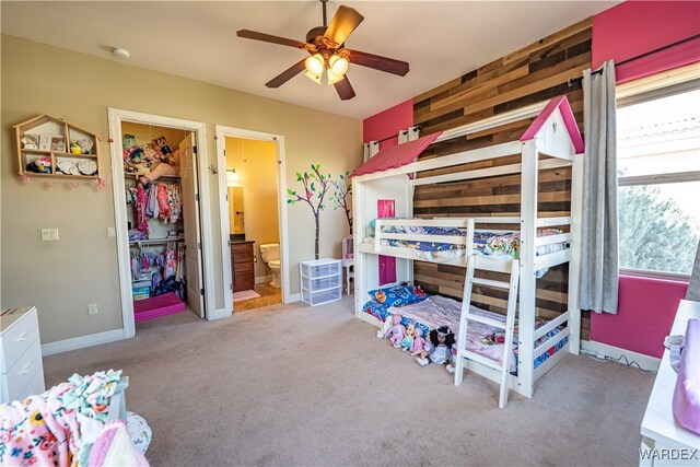 bedroom with a closet, light colored carpet, a spacious closet, connected bathroom, and baseboards