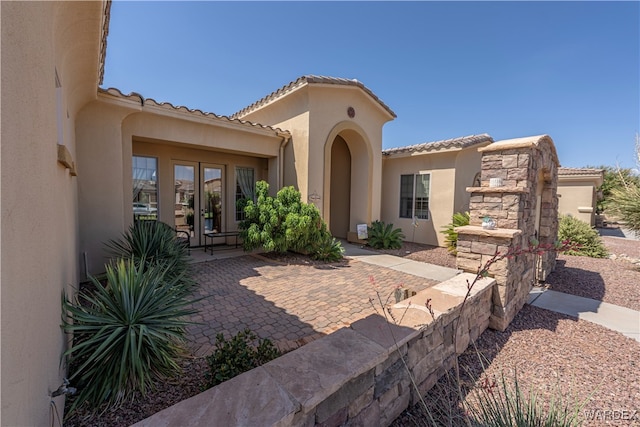 exterior space featuring stone siding, a patio area, and stucco siding