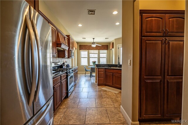 kitchen with pendant lighting, stainless steel appliances, dark countertops, a sink, and baseboards