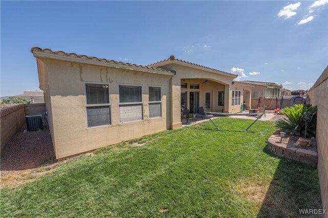 rear view of property featuring stucco siding, a fenced backyard, a lawn, and a patio