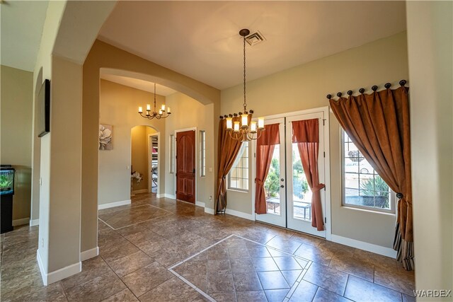 entryway with a chandelier, arched walkways, visible vents, and baseboards