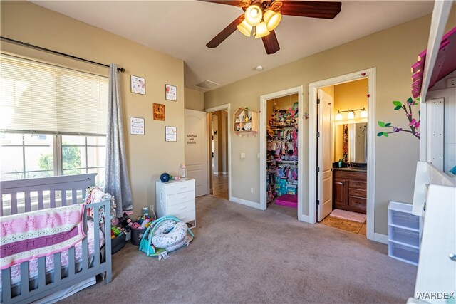 bedroom featuring baseboards, ensuite bathroom, a ceiling fan, and light colored carpet