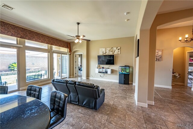 living room with arched walkways, visible vents, baseboards, and ceiling fan with notable chandelier