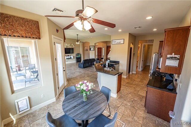 kitchen featuring dark countertops, open floor plan, visible vents, and arched walkways