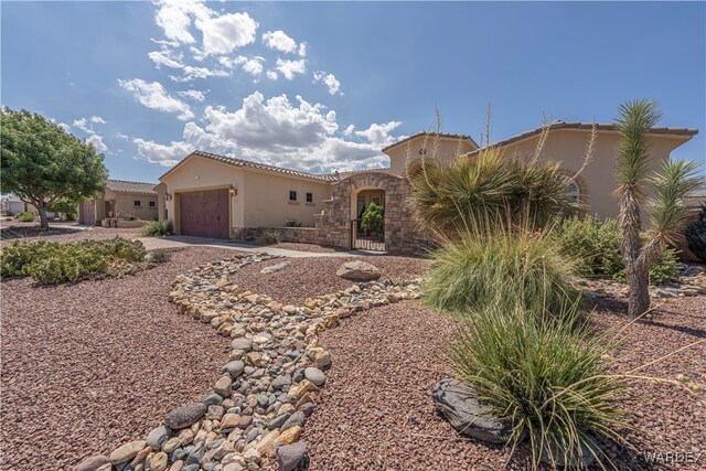 mediterranean / spanish-style home featuring a garage, a tile roof, stone siding, driveway, and stucco siding