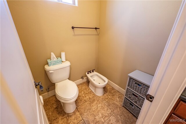 bathroom with baseboards, a bidet, toilet, and heating unit