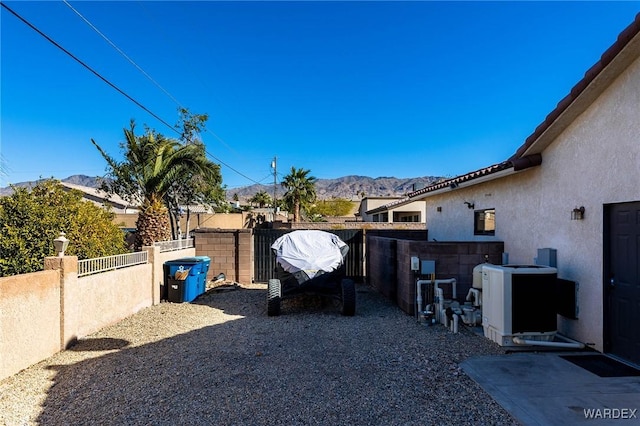 view of yard with a mountain view, fence, and central AC unit