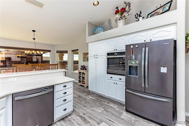 kitchen featuring visible vents, decorative light fixtures, stainless steel appliances, light countertops, and white cabinetry