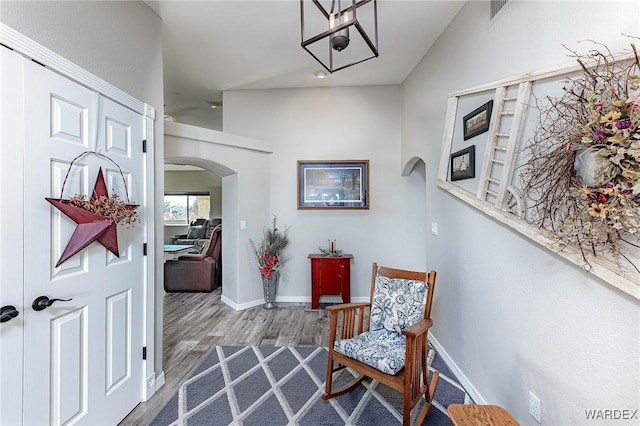 interior space featuring arched walkways, visible vents, baseboards, and wood finished floors