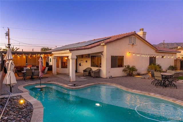 rear view of property featuring a patio area, a fenced in pool, and stucco siding