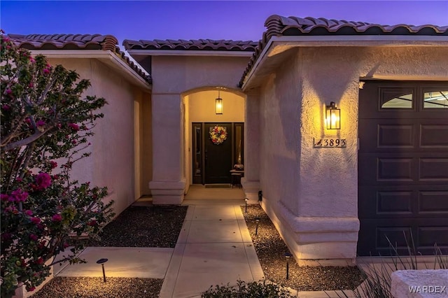 view of exterior entry with a tile roof and stucco siding