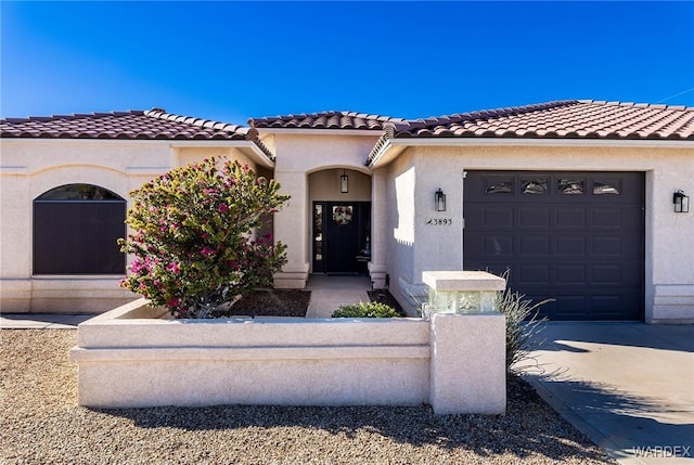 mediterranean / spanish home with a garage, a tiled roof, concrete driveway, and stucco siding