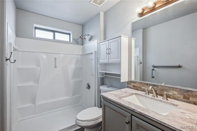 full bathroom with toilet, a stall shower, visible vents, and vanity