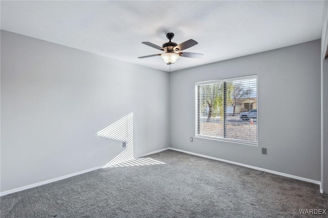 spare room featuring ceiling fan, dark colored carpet, and baseboards