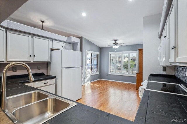 kitchen featuring ceiling fan, white appliances, a sink, light wood-style floors, and dark countertops