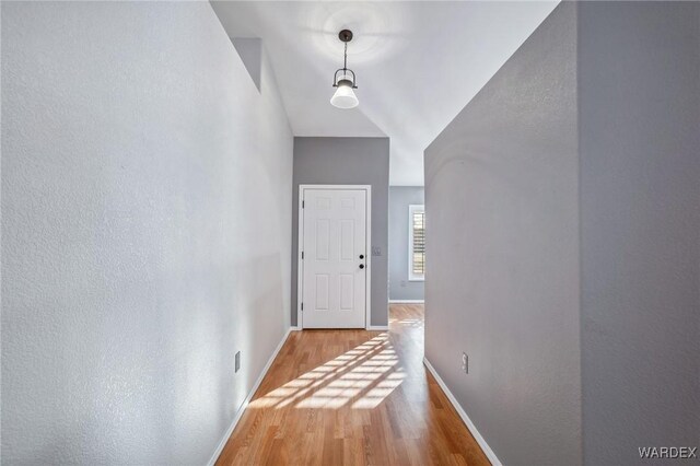 hallway featuring light wood-style flooring and baseboards