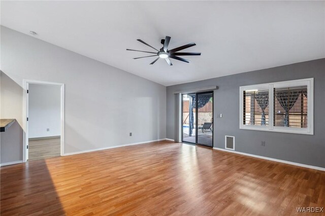 unfurnished living room with ceiling fan, vaulted ceiling, baseboards, and wood finished floors