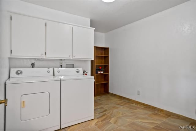 clothes washing area with baseboards, stone finish floor, cabinet space, and washer and dryer