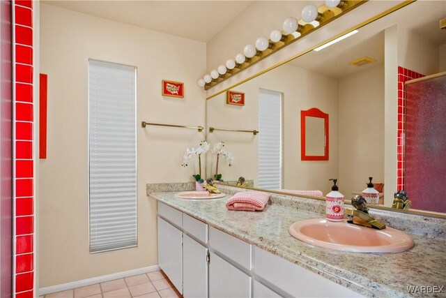 bathroom featuring tile patterned flooring, a sink, baseboards, and double vanity