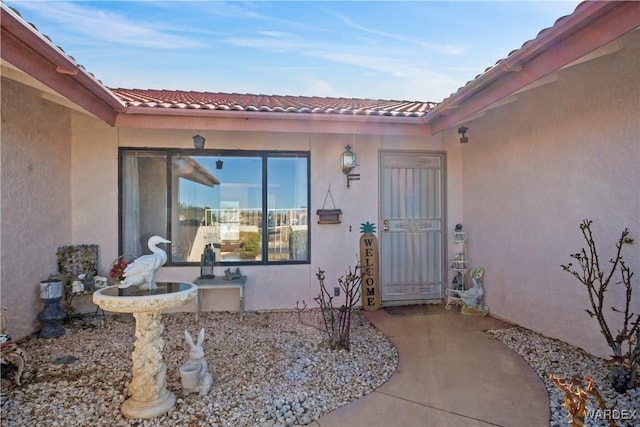 entrance to property with a tiled roof and stucco siding