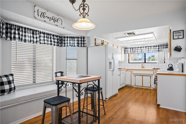 kitchen with light wood-type flooring, white appliances, visible vents, and light countertops