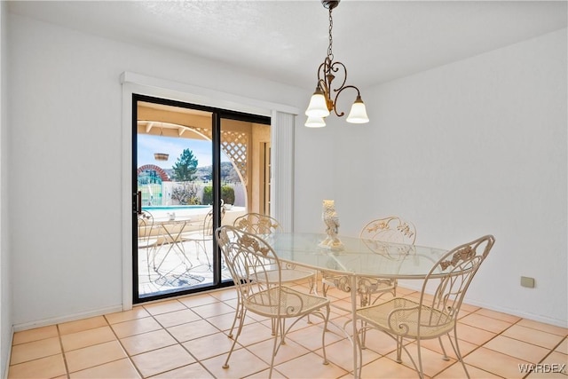 unfurnished dining area featuring a notable chandelier, baseboards, and tile patterned floors