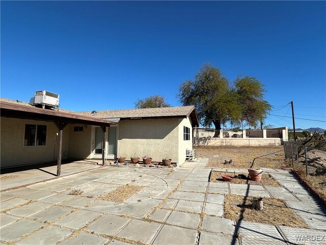 back of house featuring a patio area, a fenced backyard, central AC, and stucco siding