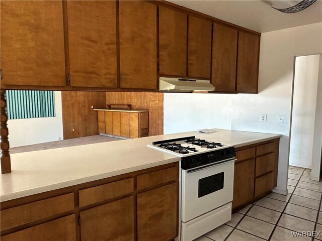 kitchen featuring light countertops, white gas stove, and under cabinet range hood