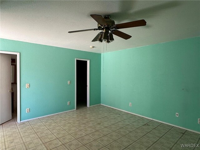 spare room featuring a textured ceiling, a ceiling fan, and baseboards