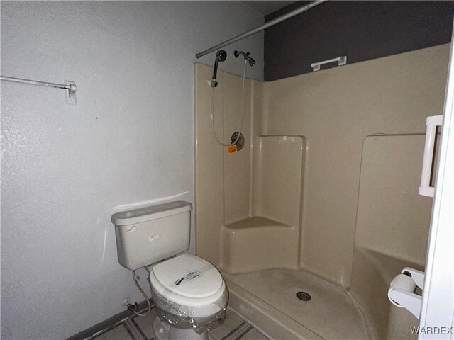 bathroom featuring a stall shower and toilet