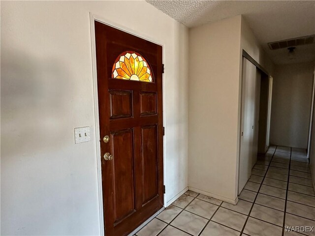 entrance foyer featuring light tile patterned floors, a textured ceiling, and visible vents