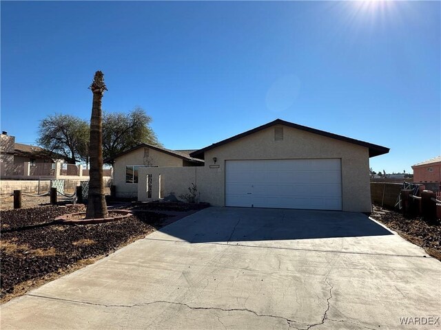 single story home with fence, driveway, an attached garage, and stucco siding