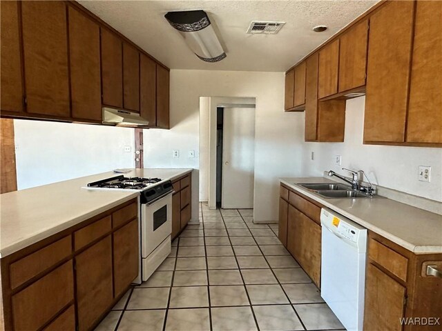 kitchen with visible vents, light countertops, a sink, white appliances, and under cabinet range hood