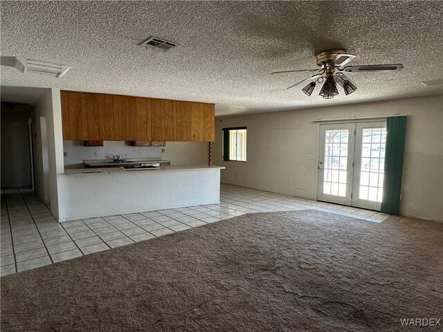 kitchen with brown cabinetry, open floor plan, light colored carpet, and light tile patterned floors