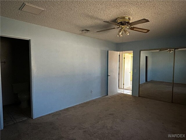 unfurnished bedroom with a closet, visible vents, light carpet, and ensuite bathroom