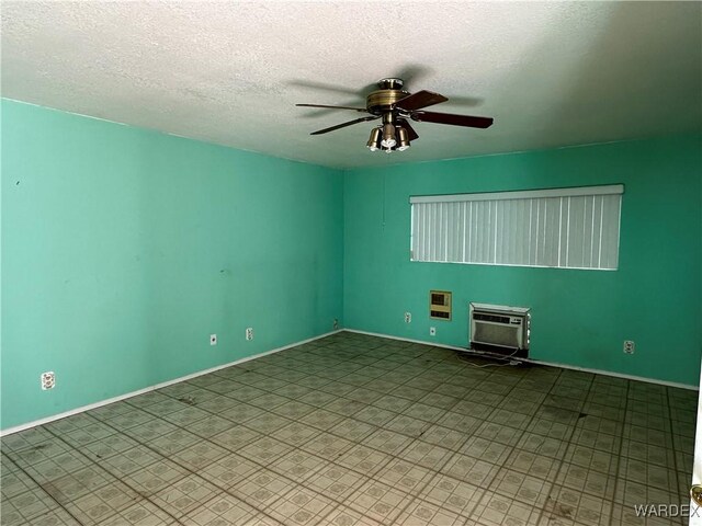 unfurnished room with a textured ceiling, baseboards, a ceiling fan, and a wall mounted air conditioner