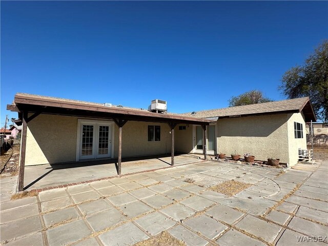 rear view of house with french doors, a patio, and stucco siding