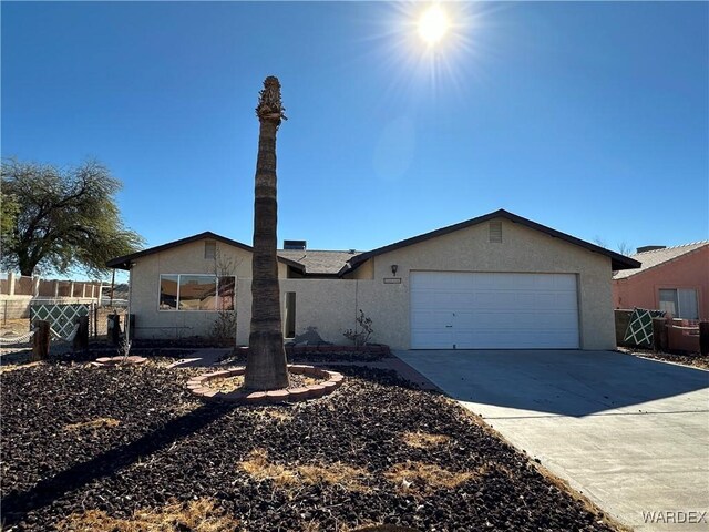 view of front of property with driveway, an attached garage, fence, and stucco siding