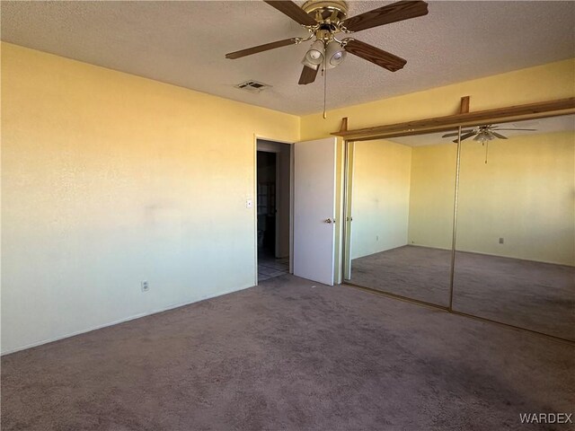 unfurnished bedroom featuring carpet floors, a closet, visible vents, a ceiling fan, and a textured ceiling