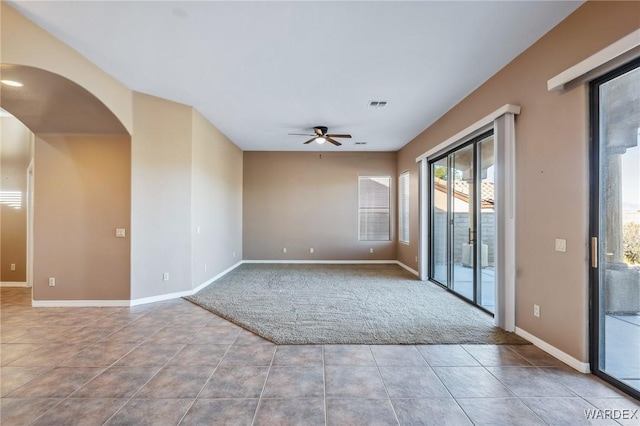 unfurnished room featuring light tile patterned floors, visible vents, arched walkways, baseboards, and ceiling fan