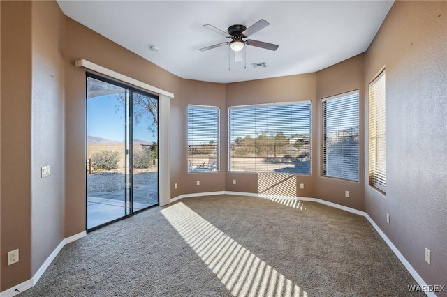 empty room featuring ceiling fan, carpet floors, visible vents, and baseboards