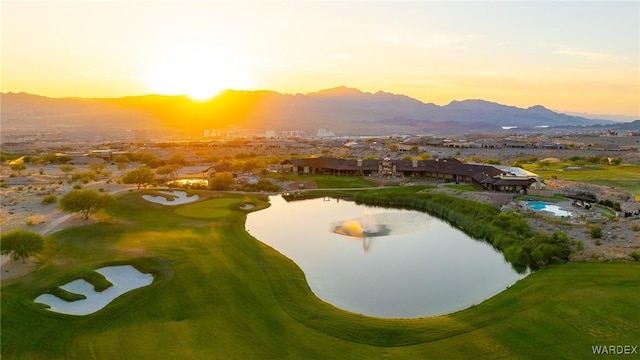 aerial view at dusk featuring golf course view and a water and mountain view