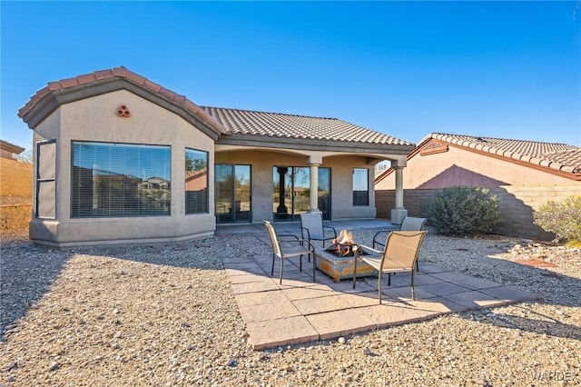 rear view of property with a patio, a fire pit, fence, a tiled roof, and stucco siding