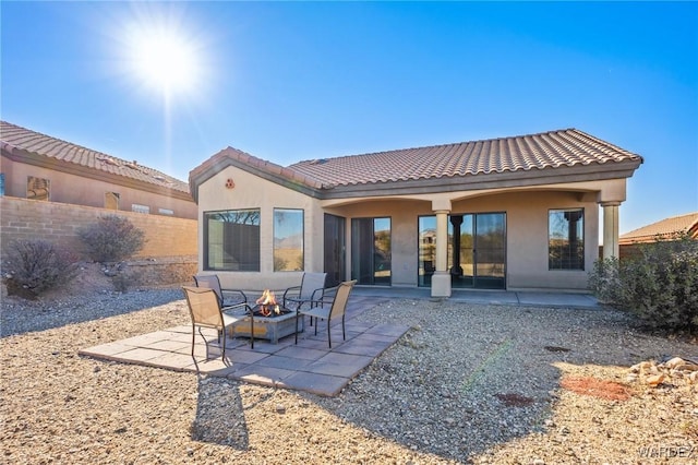 back of property with a fire pit, a patio area, fence, and stucco siding